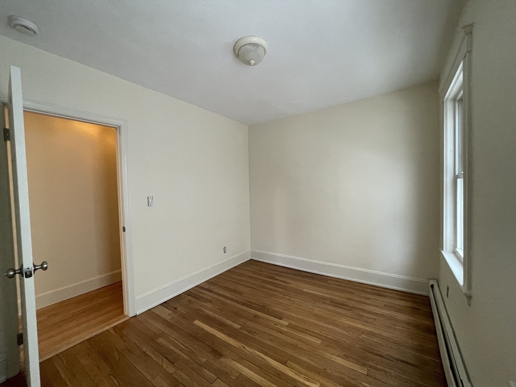 26-28 Adrian Street Somerville, MA 02143 - Photo 16 of 32 a view of an empty room with wooden floor and a window
