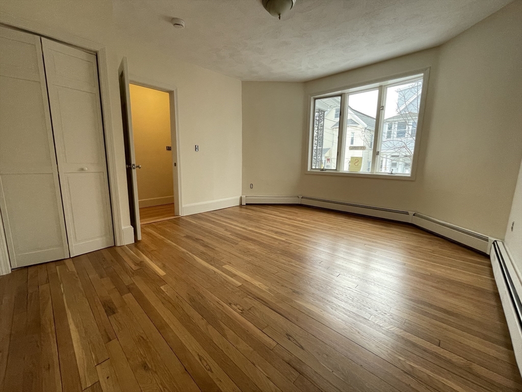 26-28 Adrian Street Somerville, MA 02143 - Photo 5 of 32 a view of an empty room with wooden floor and a window