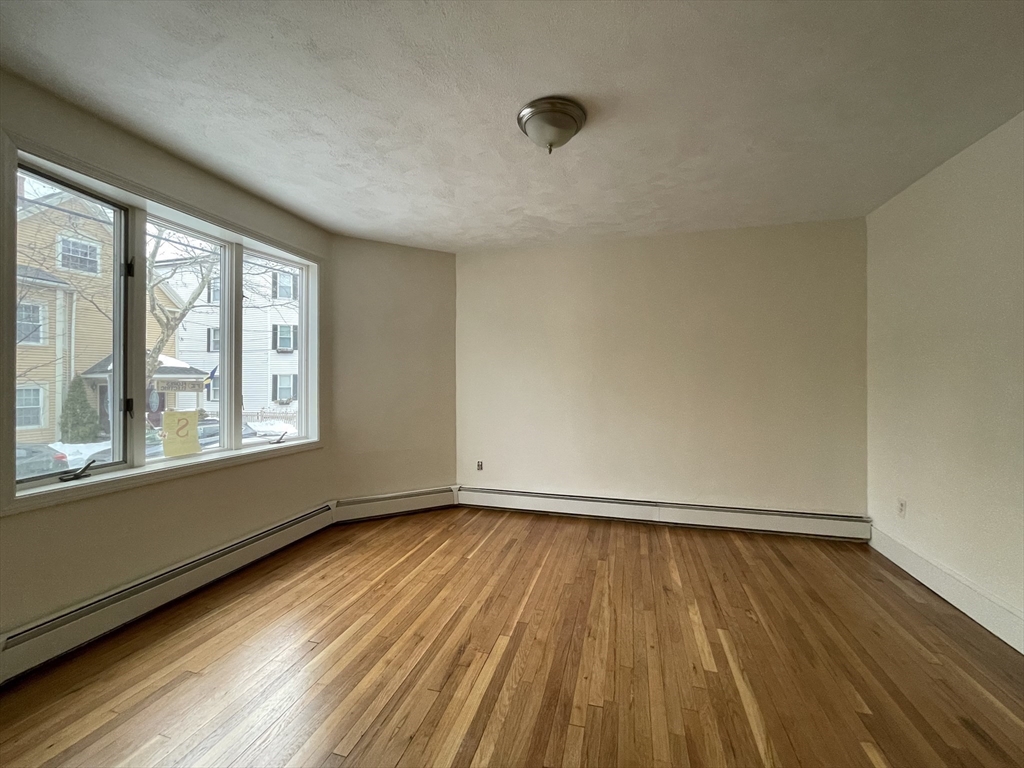 26-28 Adrian Street Somerville, MA 02143 - Photo 6 of 32 an empty room with wooden floor and windows