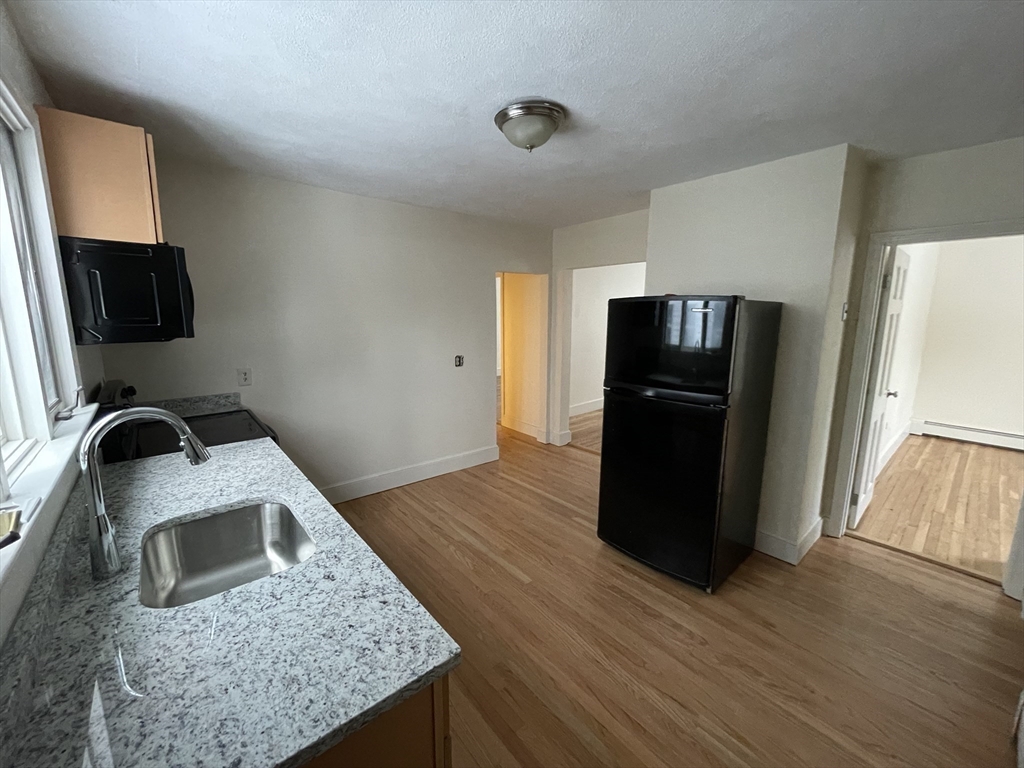 26-28 Adrian Street Somerville, MA 02143 - Photo 7 of 32 a kitchen with a refrigerator a stove and a wooden floor
