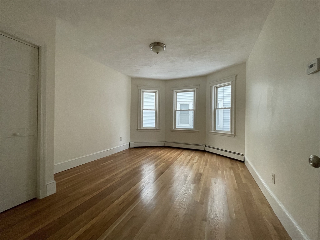 26-28 Adrian Street Somerville, MA 02143 - Photo 10 of 32 a view of an empty room with wooden floor and window