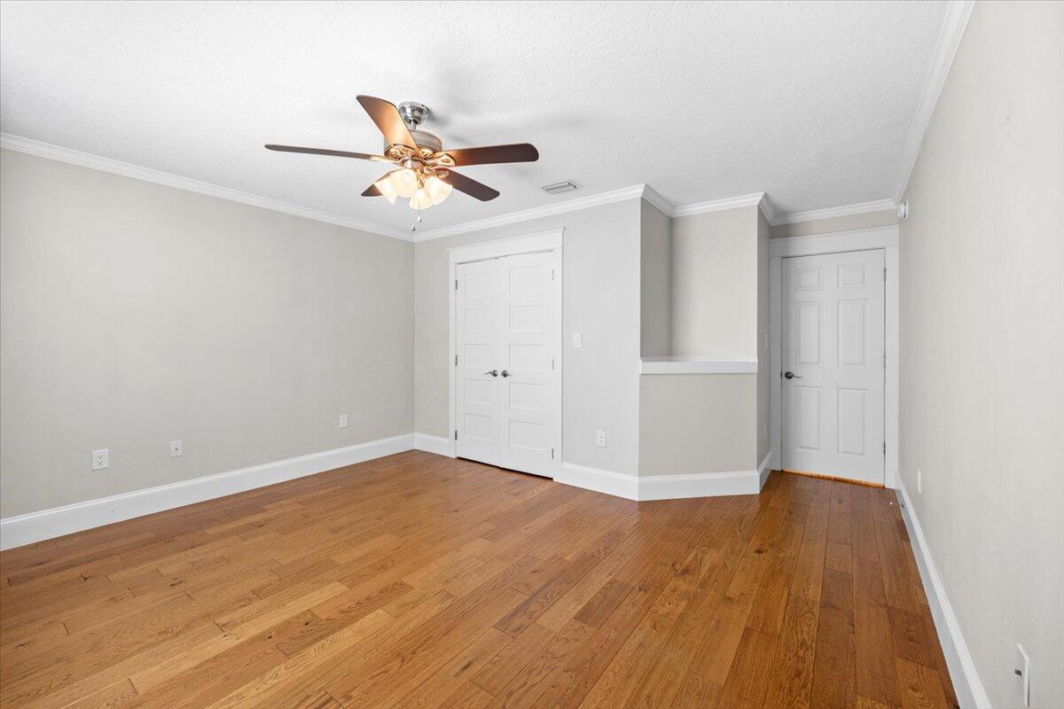 7584 Woodmont Road Navarre, FL 32566 - Photo 25 of 62 an empty room with wooden floor ceiling fan and window