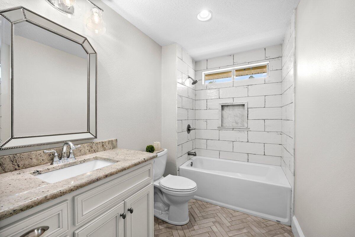 7584 Woodmont Road Navarre, FL 32566 - Photo 26 of 62 a bathroom with a granite countertop sink toilet a large mirror and shower