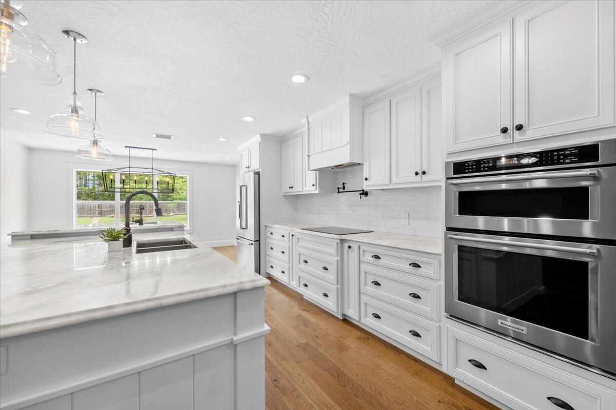 7584 Woodmont Road Navarre, FL 32566 - Photo 7 of 62 a kitchen with granite countertop a stove a sink and a counter space