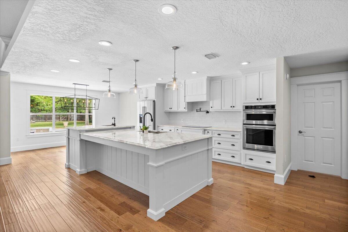 7584 Woodmont Road Navarre, FL 32566 - Photo 8 of 62 a kitchen with stainless steel appliances kitchen island granite countertop a stove a sink and a refrigerator