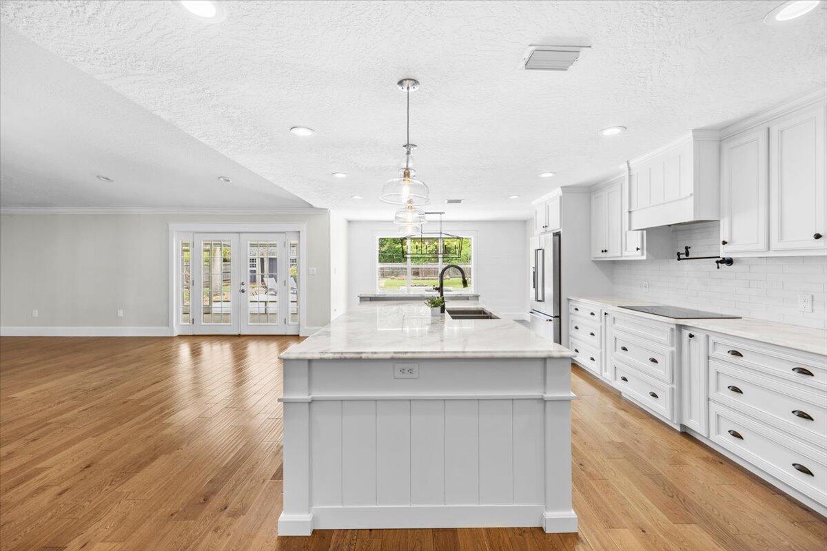 7584 Woodmont Road Navarre, FL 32566 - Photo 9 of 62 a kitchen with granite countertop a stove a sink and white cabinets with wooden floor