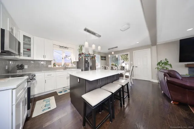 a kitchen with kitchen island a dining table chairs stainless steel appliances and cabinets