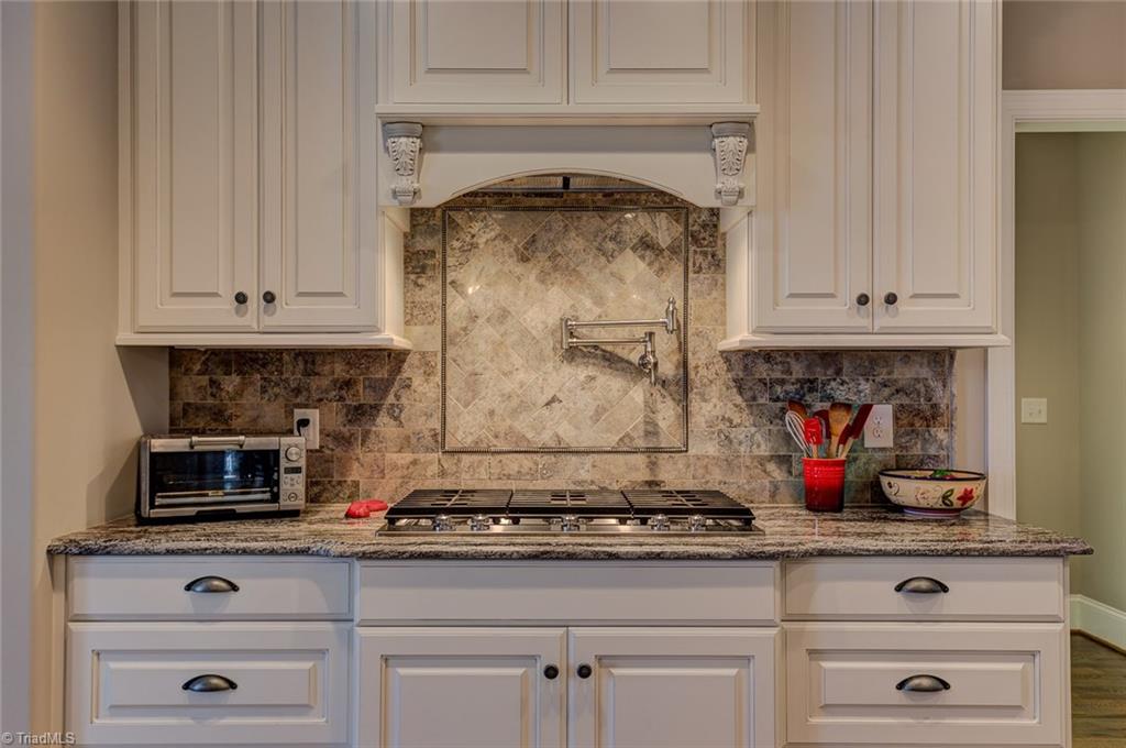 7500 Hearthridge Court Oak Ridge, NC 27310 - Photo 9 of 30 Custom tile work, custom cabinets, gas cook top, built in oven - this kitchen has so much to offer.