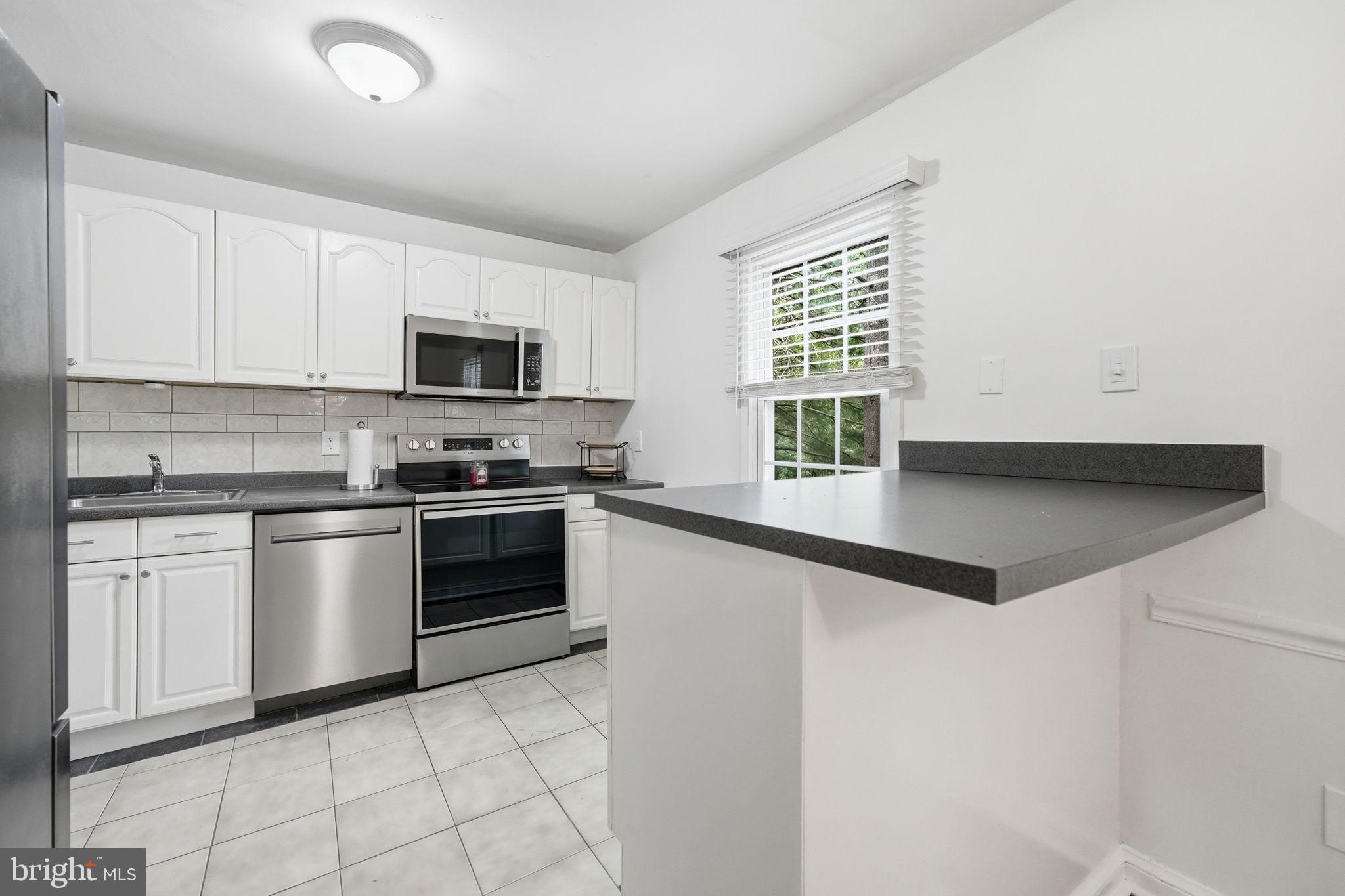 8260 Getty Court Springfield, VA 22153 - Photo 11 of 31 a kitchen with a stove a sink and a microwave
