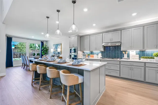 a kitchen with kitchen island granite countertop a sink a stove a dining table and chairs