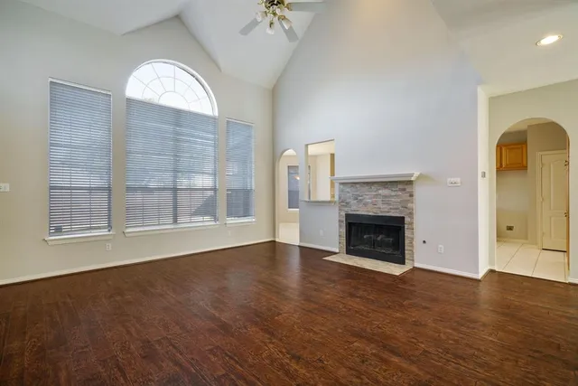 a view of an empty room with wooden floor fireplace and a window