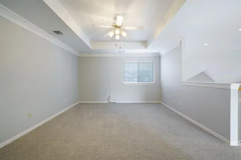 an empty room with a chandelier fan and windows