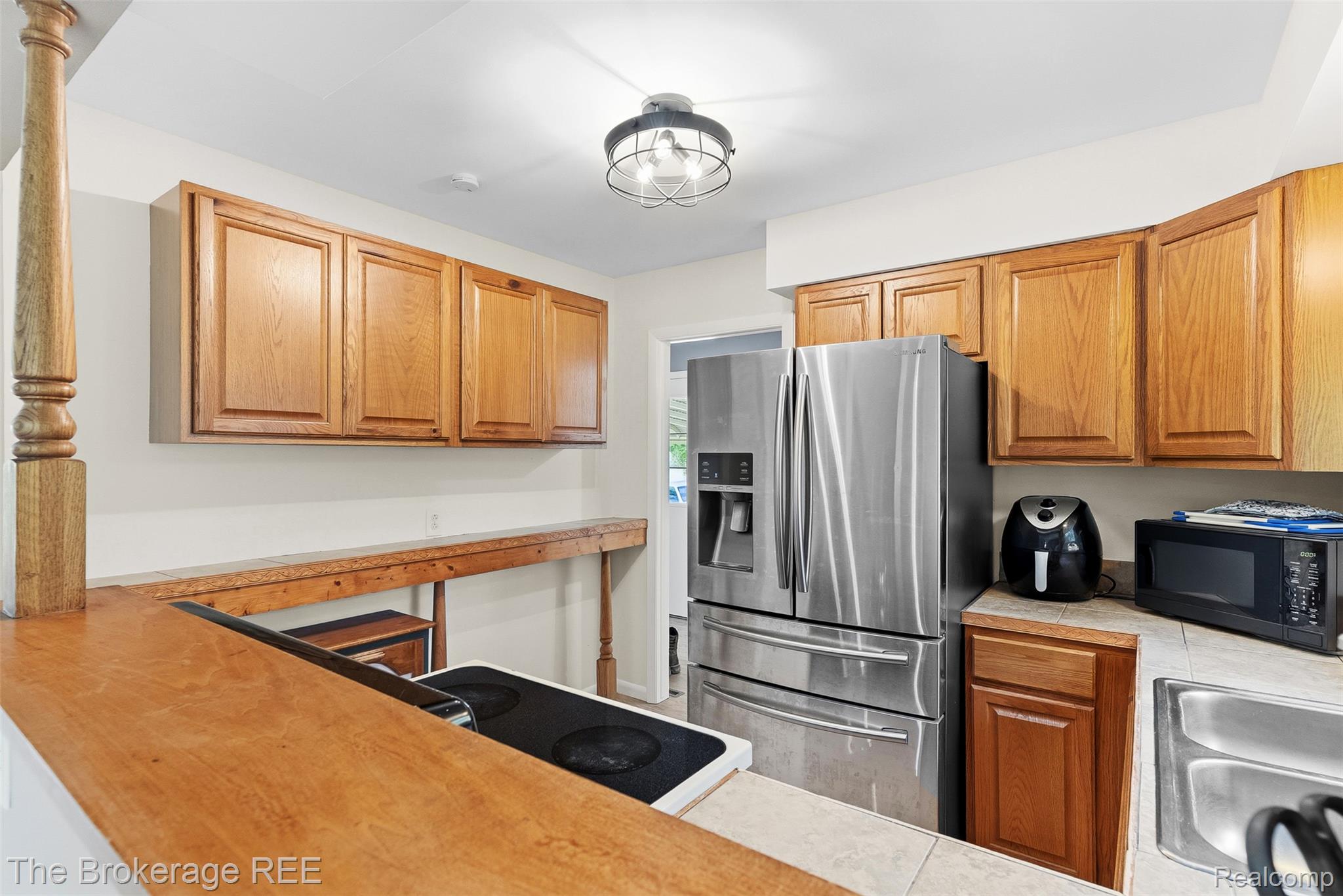 6509 Silver Lake Road Linden, MI 48451 - Photo 19 of 43 Kitchen featuring wood cabinetry, stainless steel French door refrigerator, recessed sink, and a breakfast bar with a built-in stovetop