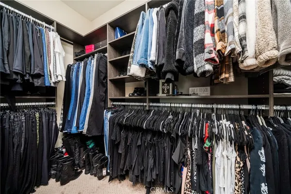 a view of walk in closet with clothes and shoes
