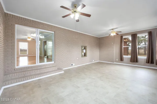 a view of an empty room with a window and a kitchen