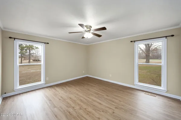 a view of an empty room with a window and wooden floor