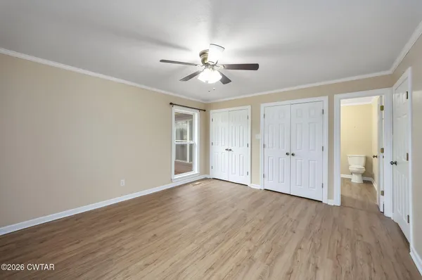 a view of empty room with wooden floor and fan