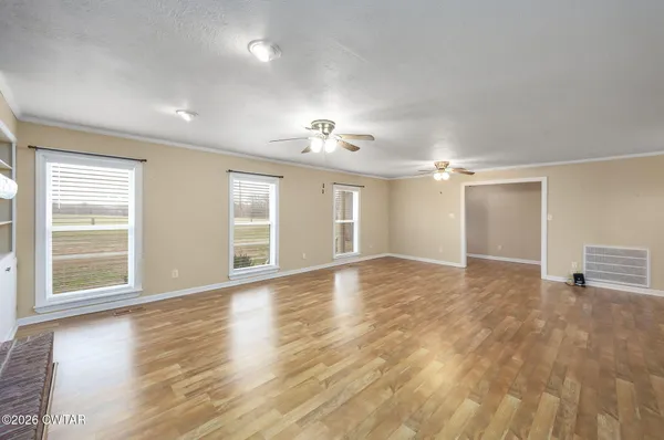 a view of an empty room with a window and wooden floor