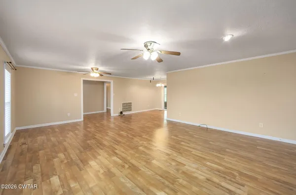 a view of empty room with wooden floor and ceiling fan