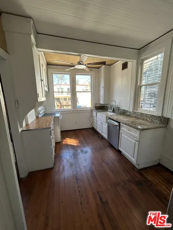 a room with stainless steel appliances wooden floors and white walls