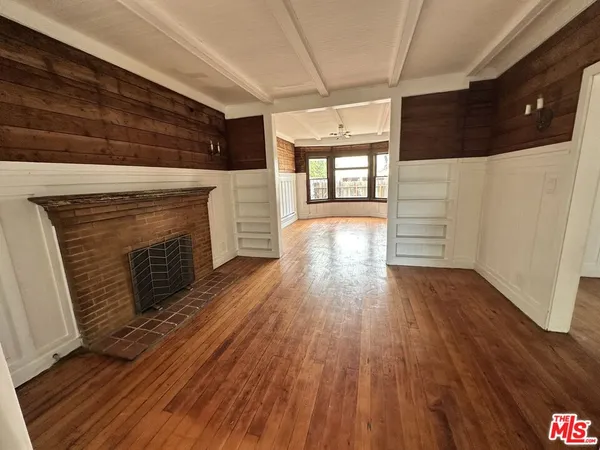 a view of an empty room with wooden floor and a fireplace