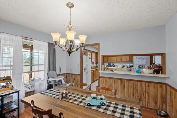 a dining room with wooden floor a chandelier a wooden table and chairs