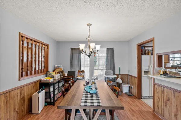 a dining room with wooden floor a chandelier a wooden table and chairs