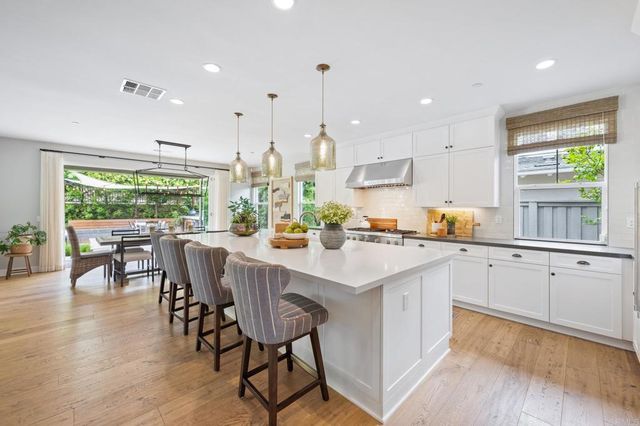 a kitchen with stainless steel appliances granite countertop table chairs sink and stove