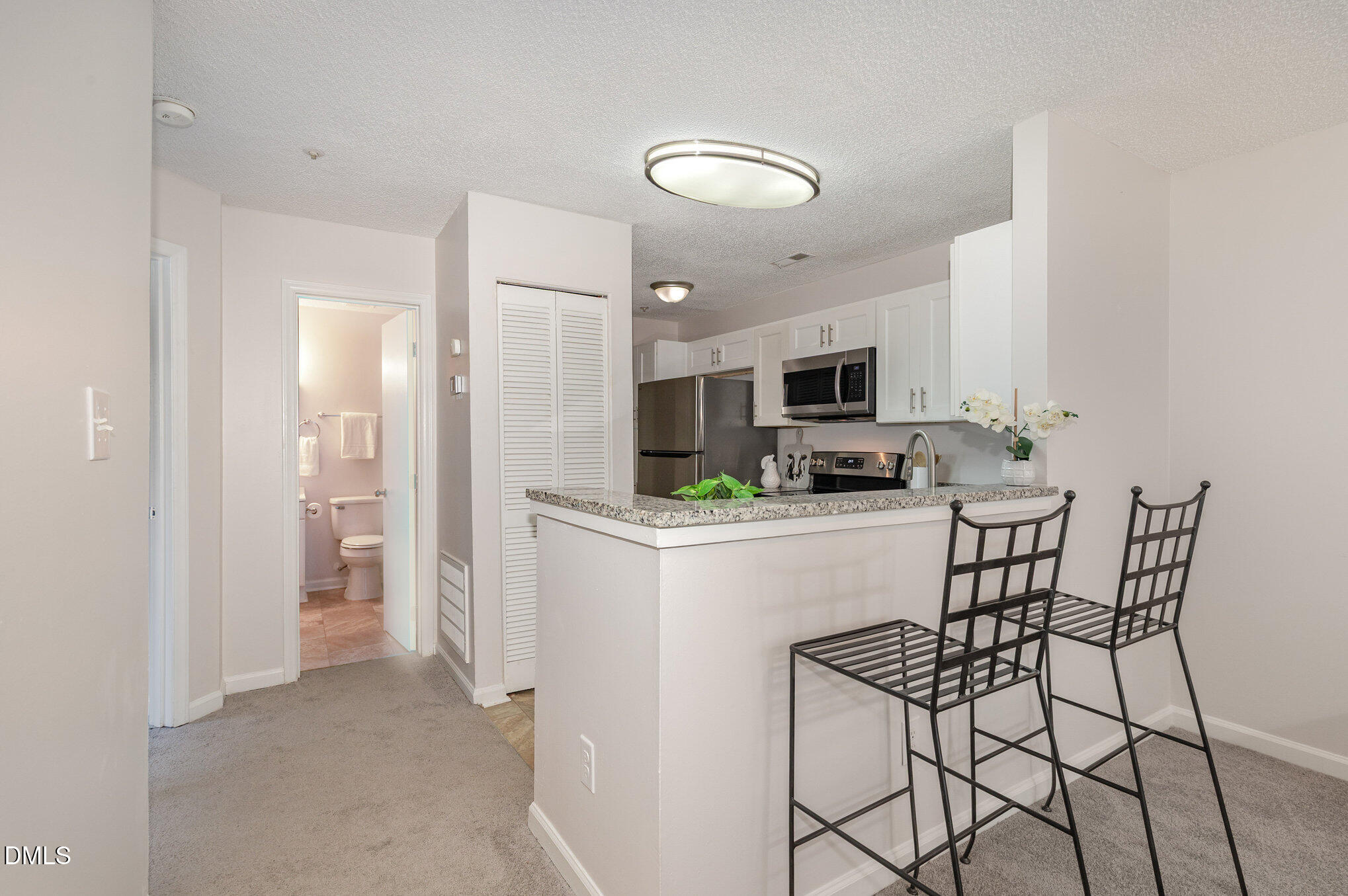 4911 Hollenden Drive, Unit 108 Raleigh, NC 27616 - Photo 7 of 19 a kitchen with stainless steel appliances kitchen island granite countertop a refrigerator and microwave