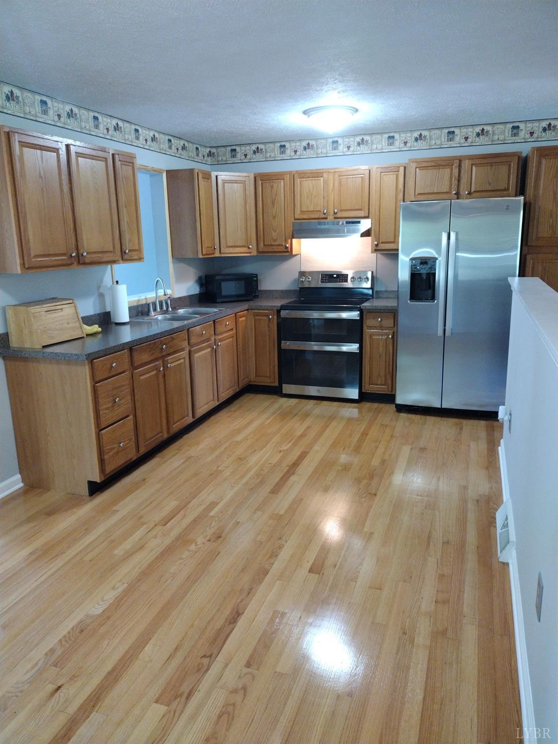 4499 Stage Road Concord, VA 24538 - Photo 10 of 64 a kitchen with stainless steel appliances wooden floors and wooden cabinets