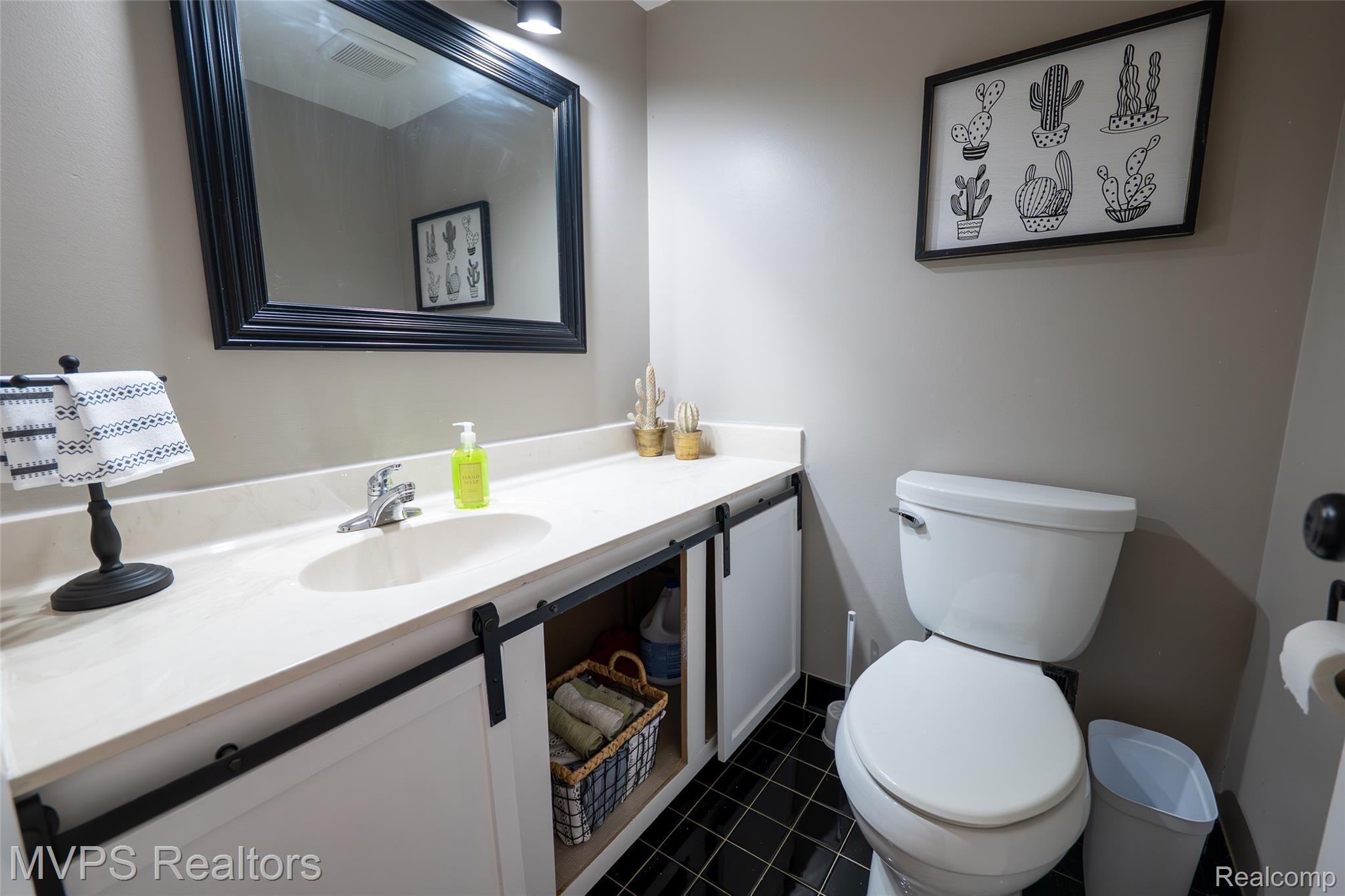 804 Oak Brook Ridge Drive, Unit 149 Rochester, MI 48307 - Photo 16 of 49 Bathroom featuring a white vanity with sliding barn-door style cabinet fronts, an oval undermount sink, and a framed mirror