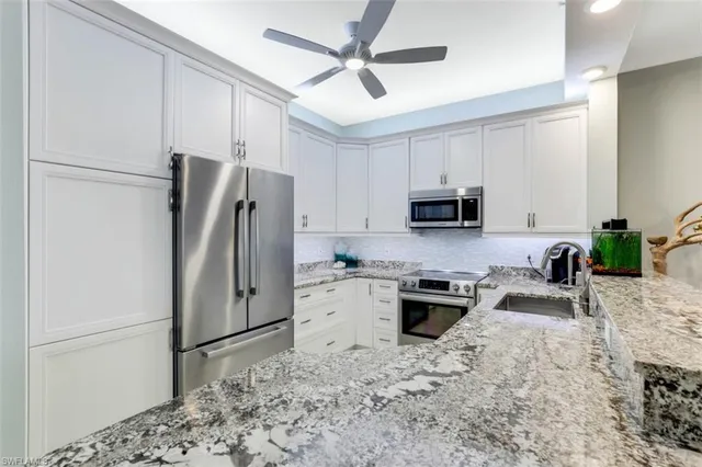 a kitchen with granite countertop a refrigerator stove and microwave