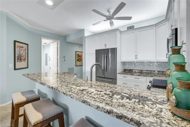 a kitchen with stainless steel appliances granite countertop sink stove refrigerator and cabinets