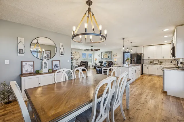 a dining room with wooden floor a chandelier a wooden table and chairs