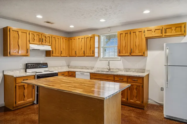 a kitchen with a sink a stove a refrigerator a center island and a window