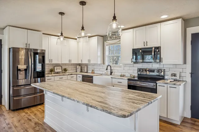 a kitchen with stainless steel appliances granite countertop a sink a stove and a refrigerator