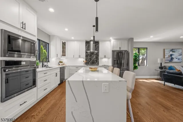 a large kitchen with kitchen island a stove a sink a oven and a dining table with wooden floor