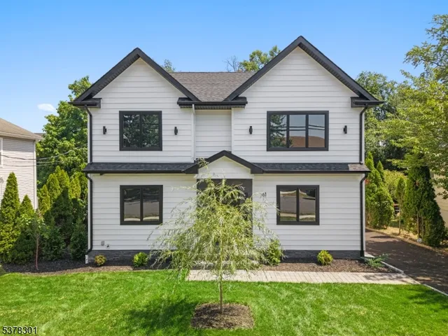 a view of a yard in front of a house with plants and large tree