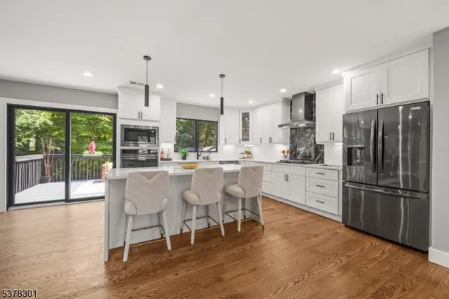 a kitchen with stainless steel appliances granite countertop a refrigerator a stove top oven and a dining table with wooden floor