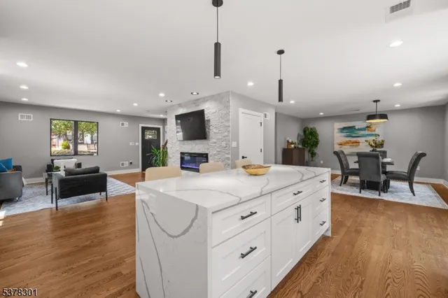 a large living room with stainless steel appliances granite countertop furniture a fireplace a flat screen tv and a couch