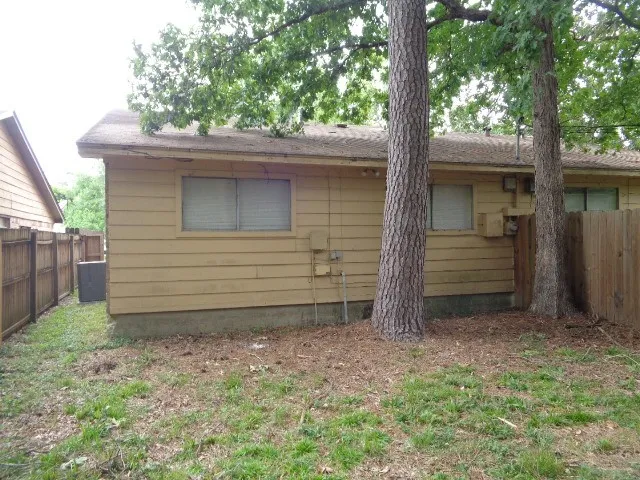 a view of wooden house with a small yard and large trees