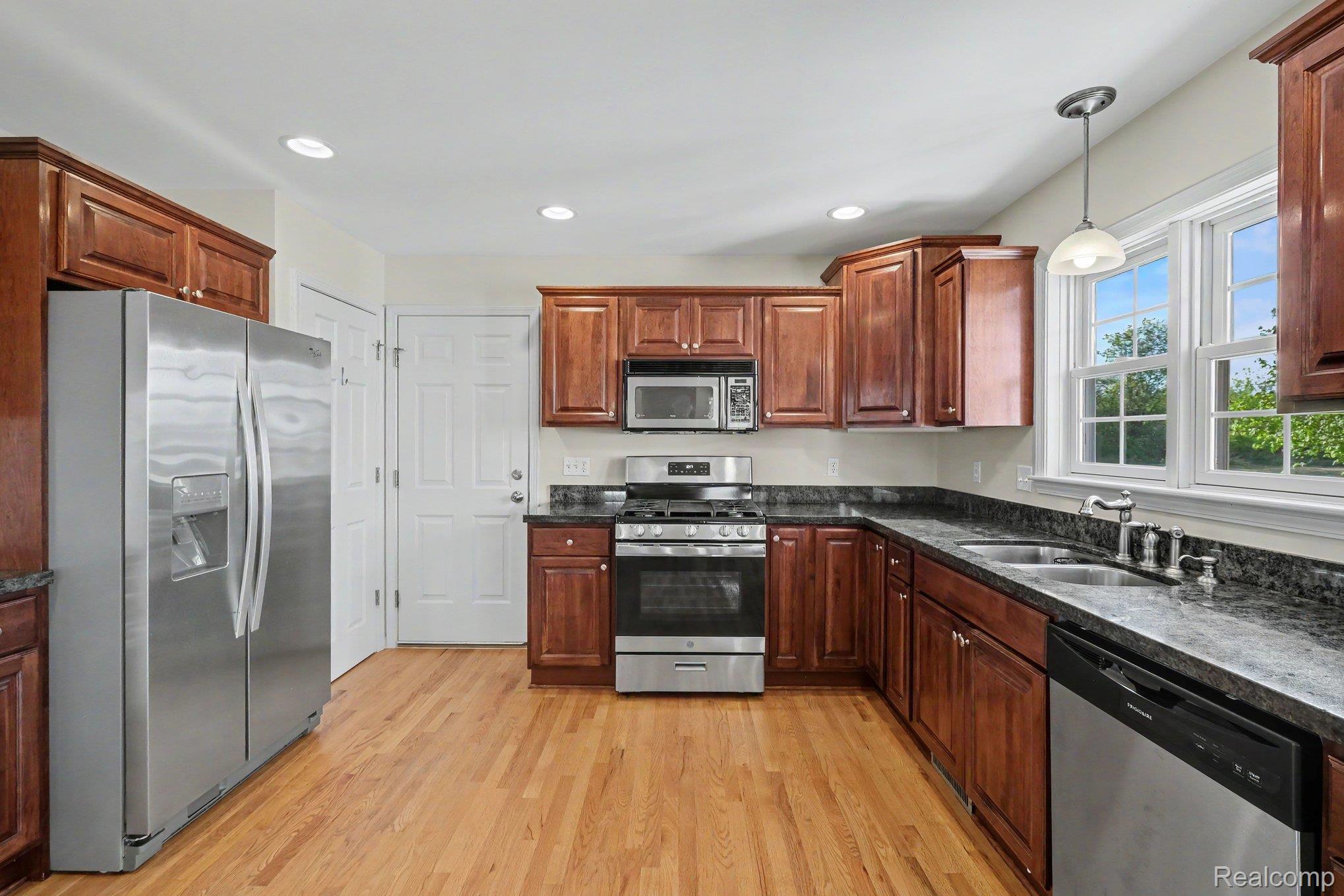 6520 Cook Road Swartz Creek, MI 48473 - Photo 16 of 43 Kitchen featuring stainless steel appliances, dark stone countertops, light wood-style floors, and pendant lighting
