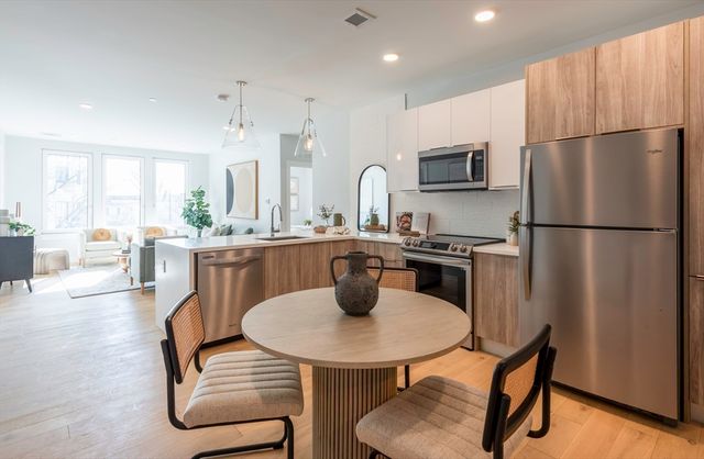 a kitchen with stainless steel appliances a table chairs microwave and refrigerator