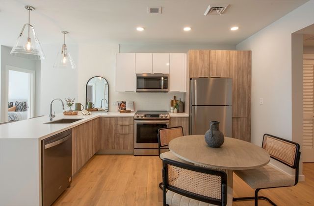 a kitchen with stainless steel appliances granite countertop a refrigerator a sink a stove a dining table and chairs