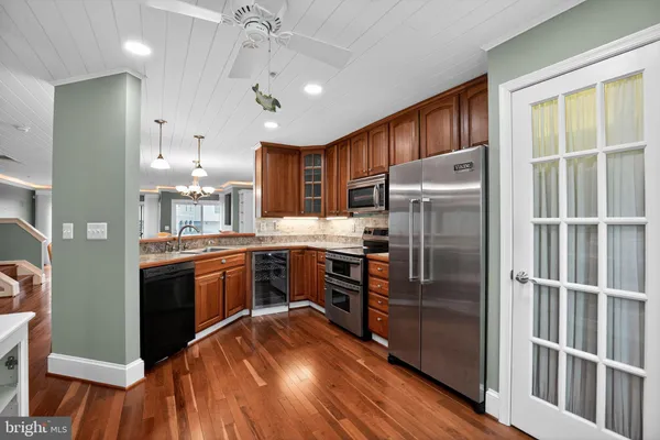 a kitchen with kitchen island granite countertop a refrigerator a sink a stove and a wooden floors