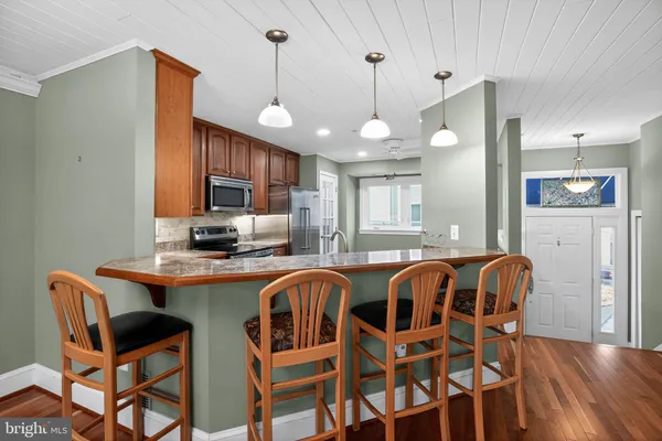 a kitchen with stainless steel appliances granite countertop a sink a stove a dining table and chairs