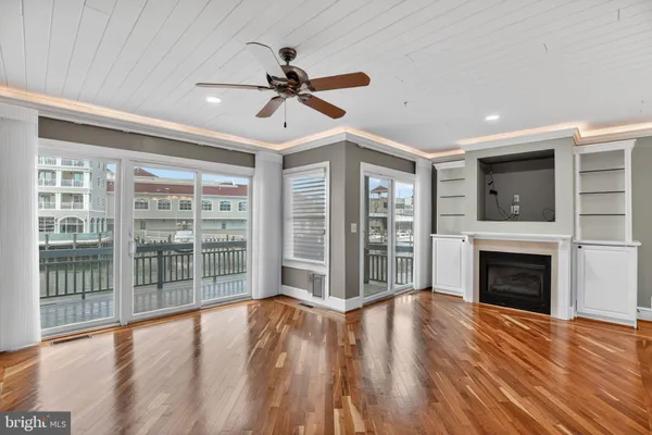 a view of an empty room with wooden floor fireplace and a window