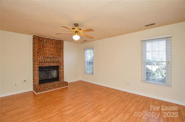 a view of a hallway with wooden floor and a bathroom