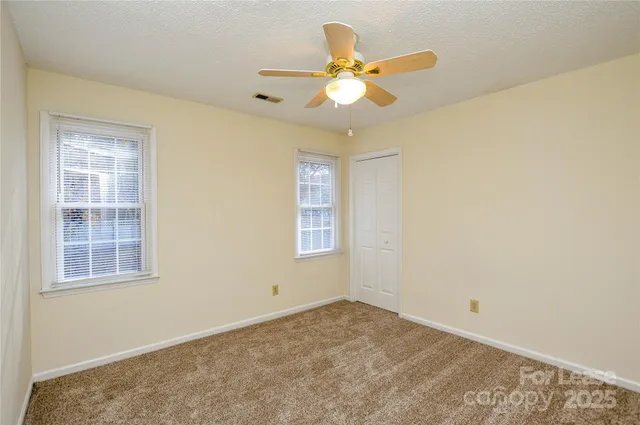 an empty room with windows and ceiling fan