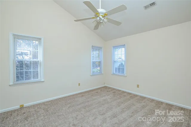 an empty room with windows and fan